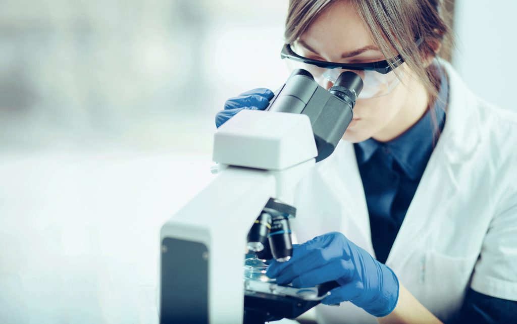 female scientist looking through microscope in lab