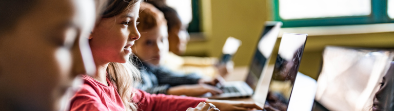 school children working in classroom on laptops
